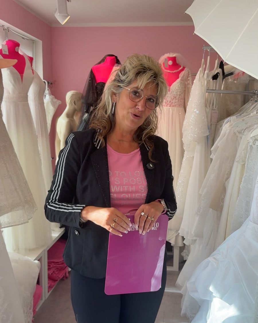 Yvonne mit Notizmappe zwischen Brautkleiden